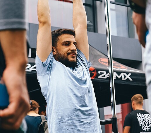 Ein junger Mann hängt an einer Klimmzugstange.