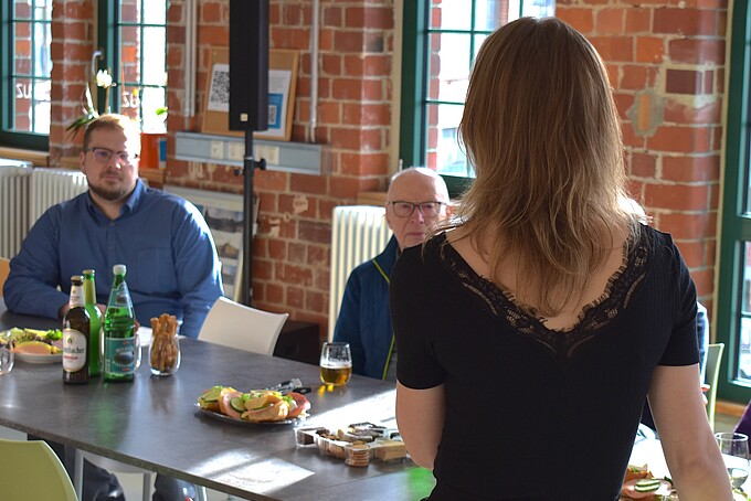 Referentin steht vor einem Tisch und spricht zur Gruppe
