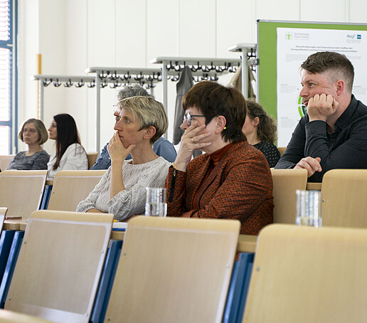 Zuhörer sitzen auf Sitzreihen im Vorlesungssaal.
