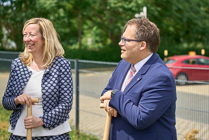 Der Rektor und die Prorektorin Forschung, Transfer und Internationales stehen auf der Wiese und unterhalten sich mit jemanden.
