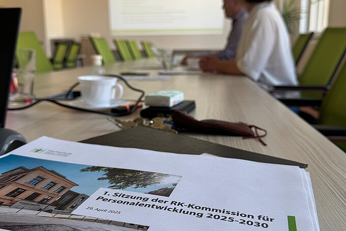 Ein ausgedrucktes Papier mit dem Deckblatt zu einer Präsentation zum Thema Personalentwicklungskommission liegt auf einem Konferenztisch.