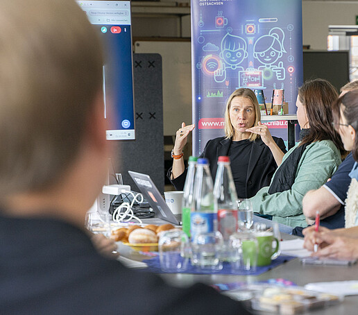 Eine Konferenzteilnehmerin diskutiert mit anderen.