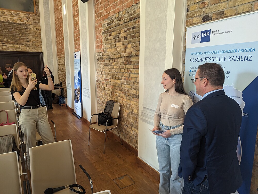 Mann und Frau vor einem Plakat mit der Überschrift IHK Geschäftsstelle Kamenz