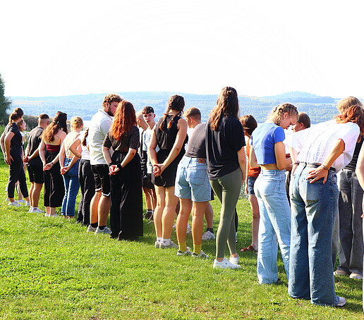 Studierende stehen in einer Reihe auf einer Wiese.