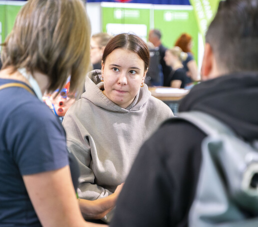 Studieninteressierte unterhalten sich mit einer Studentischen Hilfskraft.