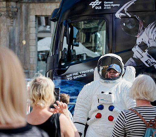 Kinder posieren mit einem Raumanzug.