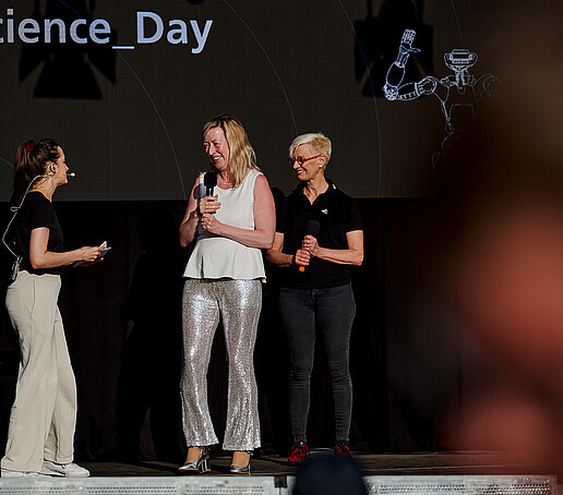 Die Prorektorin mit Mikro auf der Bühne mit zwei anderen Sprecherinnen.