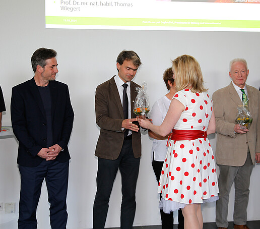 HSZG-Lehrende stehen in einer Reihe in der Aula. Die Prorektorin überreicht einem Lehrenden eine Blume.