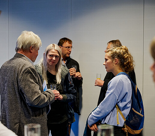 Gäste unterhalten sich beim Sektempfang.
