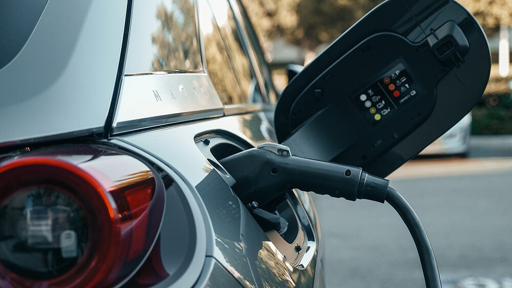 Ein Elektroauto mit geöffnetem Schutzdeckel, das Ladekabel ist angeschlossen.