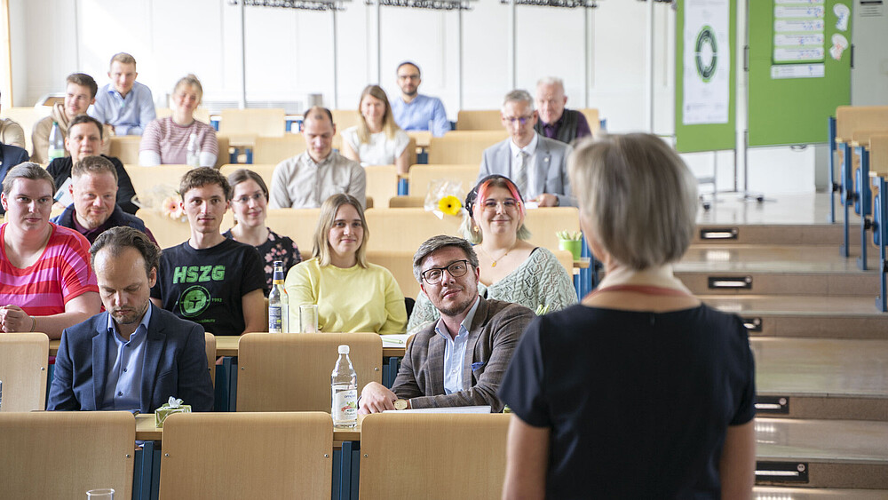 Die Prorektorin steht zu vollbesetzten Sitzreihen im Hörsaal zugewandt.