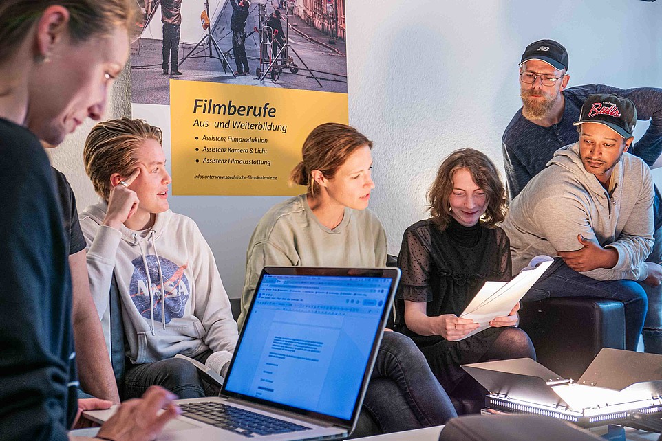 Teilnehme des Seminars Aufnahmeleitung sitzen zusammen und studieren 