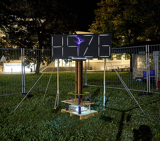 Das HSZG-Logo leuchtet hell, im Vordergrund ist ein lila Blitz zu sehen.