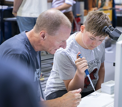 Ein Junge pipettiert an einem Versuchsstand.