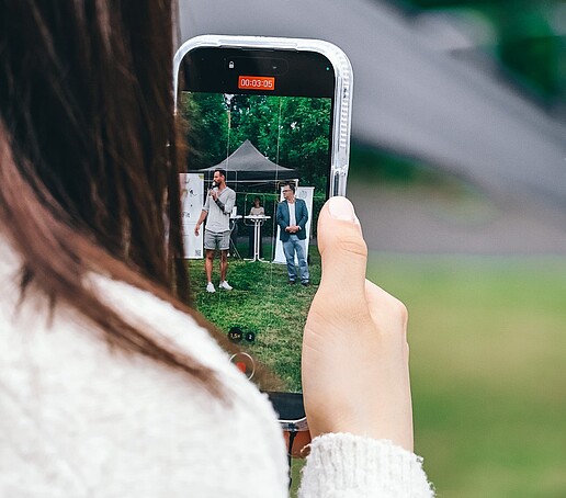 Ein Mädchen hält ihre Handykamera in der Hand, darauf ist der Rektor und Philipp Knebel zu sehen.