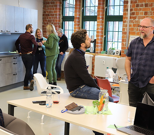 Im Küchenteil vom Celsiuz stehen Workshopteilnehmende und unterhalten sich.