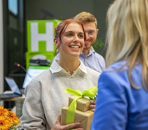 Eine Preisträgerin hält ein Geschenk in den Händen.