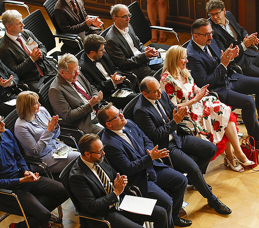 Im Bürgersaal sitzt das Publikum auf vollbesetzten Stuhlreihen und applaudiert.