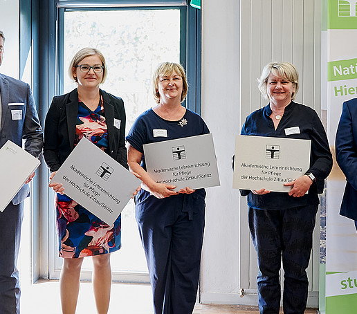Rektor mit drei Kooperationspartner im Pflegebereich. Sie halten ihr Aushängeschild und ihre Urkunde in der Hand.