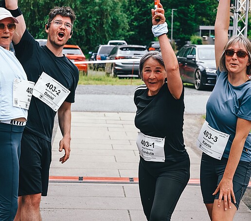 Vier Teilnehmende jubeln im Ziel und reißen die Arme hoch.