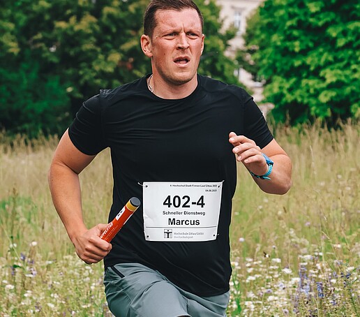 Ein Mitarbeiter der Hochschule läuft mit Staffelstab seine Runde auf dem Zittauer Campus.