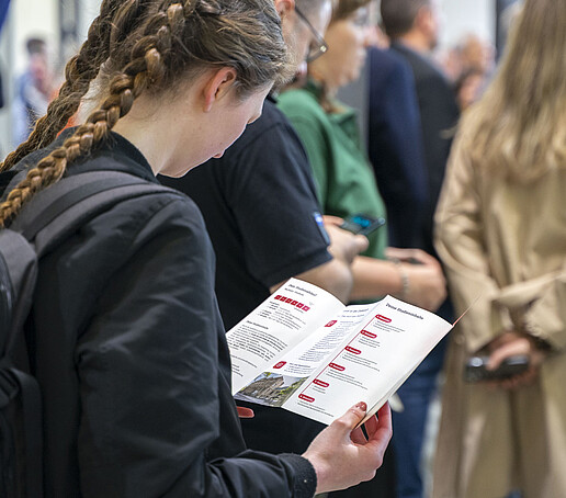 Eine Studieninteressierte liest einen Studiengangsflyer.