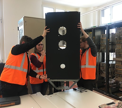 Drei Personen in Schutzwesten montieren ein Gerät