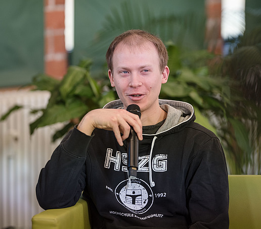 Ein Student mit Mikro auf dem Talk-Sofa