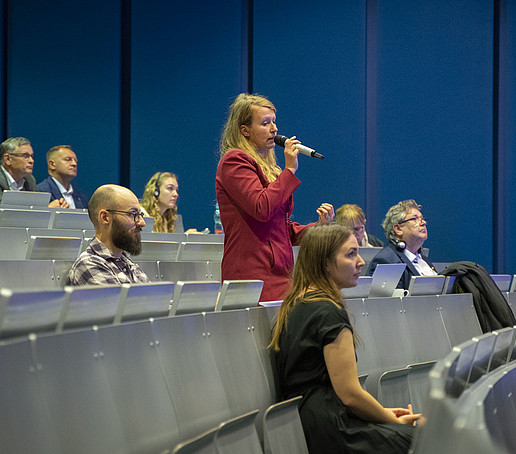 Eine Panelistin steht im Hörsaal und spricht in ein Handmikrofon.