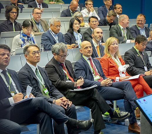 Internationale Gäste in der ersten Reihe des Hörsaals, darunter Vertretungen aus Politik, Wissenschaft und Diplomatie.