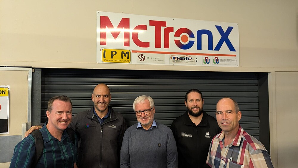 Prof. Worlitz  (Mitte) mit Prof. Kenny Uren (links) und weiteren Kollegen der NWU vor dem Mechatroniklabor der NWU