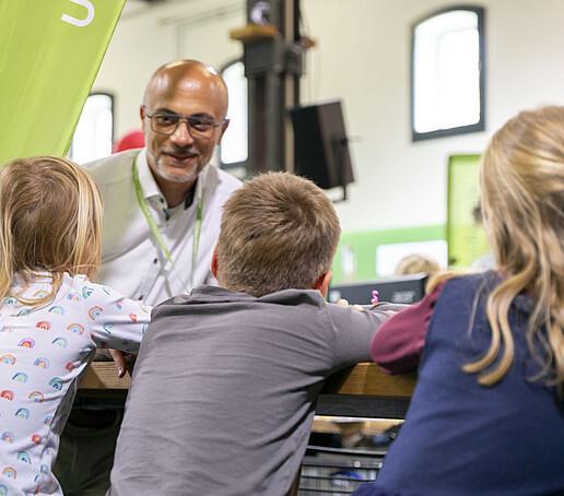 Prof. Maiwald unterhält sich mit drei Kindern.