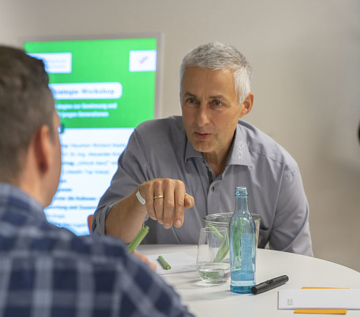 Zwei Teilnehmende sitzen am Tisch und erzählen sich etwas.