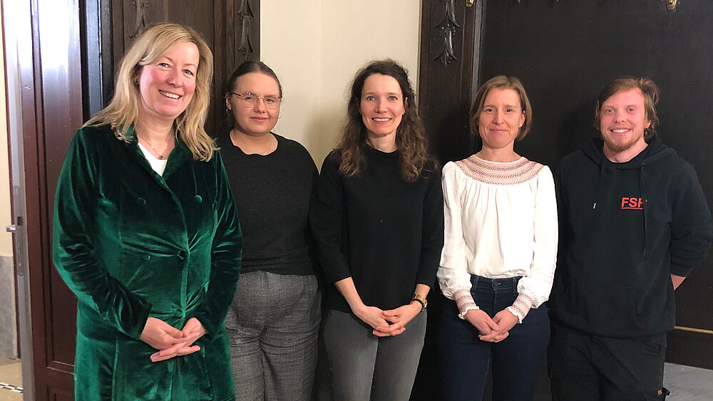 Fünf Personen stehen nebeneinander und lächeln in die Kamera.