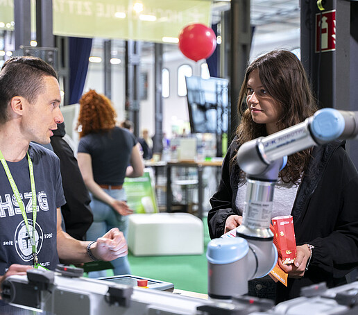 Ein Mitarbeiter erklärt einer Besucherin einen Besuchsstand.