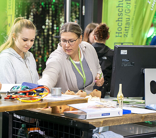 Eine Besucherin lässt sich etwas an einem Mitmach-Stand von einer Mitarbeiterin demonstrieren.