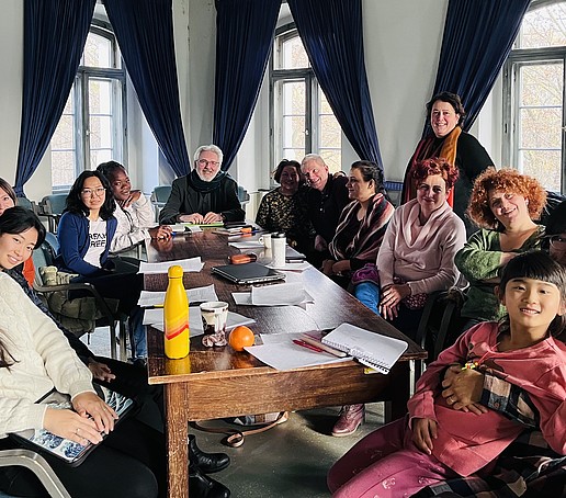 Teilnehmende am Doktorandenkolleg sitzen an einem Tisch und lächeln in die Kamera.