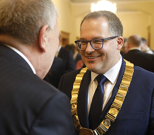 Der Rektor nimmt von einem Gast Glückwünsche entgegen.
