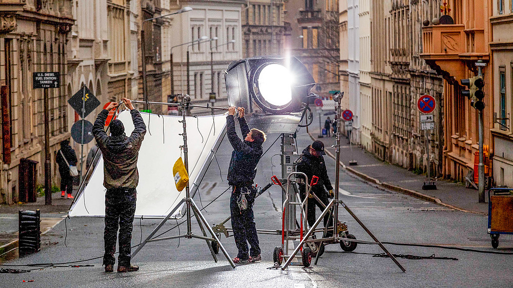 Ein Filmset in einer Görlitzer Straße. Mitarbeitende bauen Lampen auf.