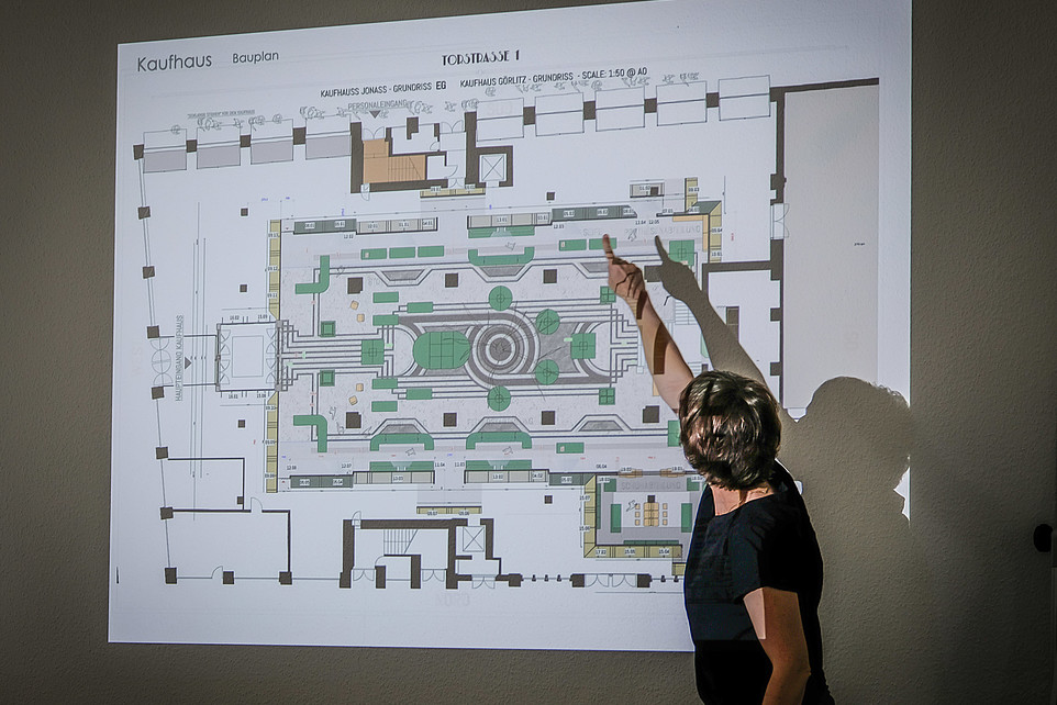 Die Dozentin erklärt den Lehrinhalt anhand einer Beamerprojektion. Zu sehen ist der Grundriss eines Filmsets.