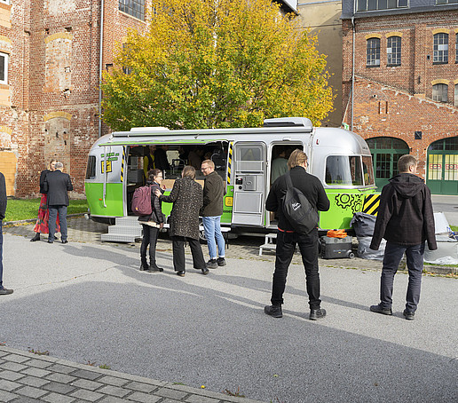 Die Gäste gehen im Hof auf den Zuklos-Anhänger zu.