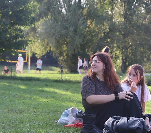 Studentinnen sitzen auf einer Picknickdecke auf einer Wiese.