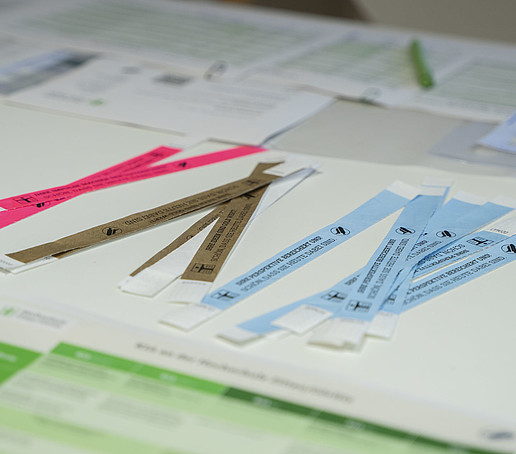 Pinke, goldene und hellblaue Einlassbändchen liegen auf einem Tisch.