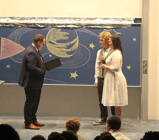 Der Rektor vermählt Grace und AJ auf der Bühne.