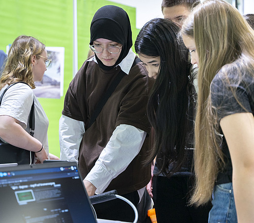 Besucherinnen informieren sich an einem Tisch bei einer Mitarbeiterin.