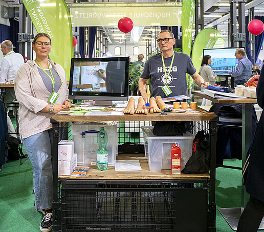Am Stand der Angewandten Pflegewissenschaft stehen zwei Mitarbeitende.
