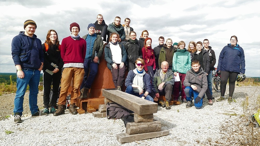 Eine Gruppe von Studierenden und einem Professor in steiniger Landschaft.