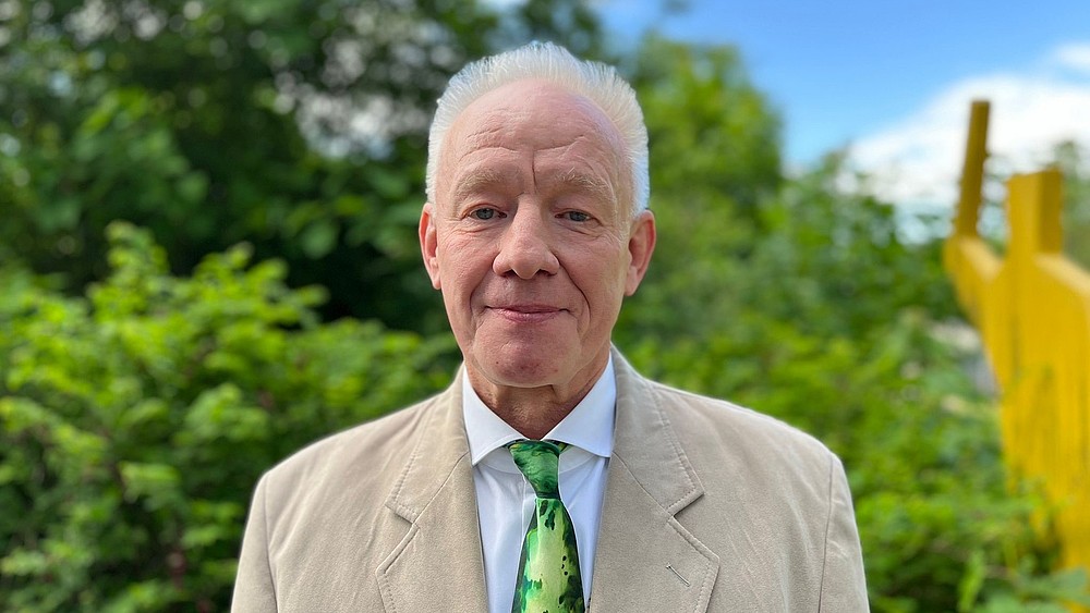 Prof. Kästner steht im Freien am Campus Görlitz im Anzug und lächelt in die Kamera.