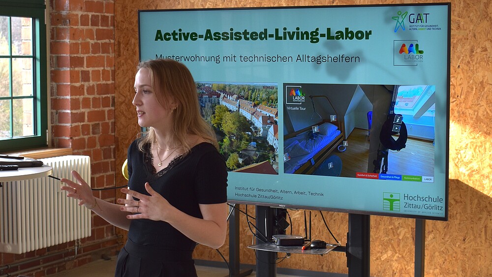 Frau referiert vor einem Monitor