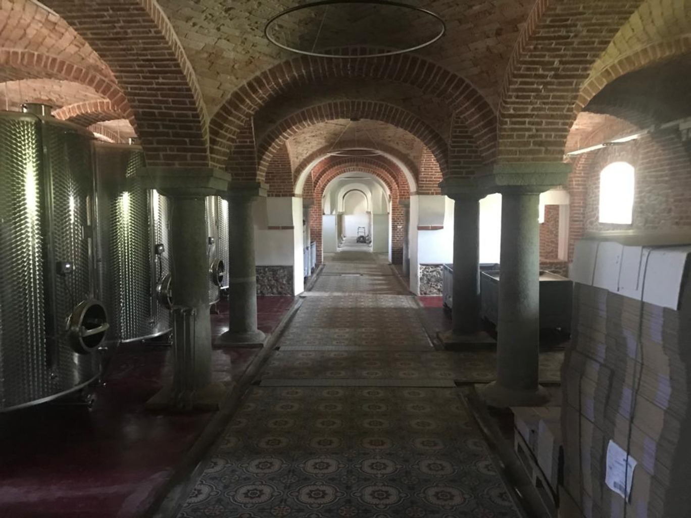 Blick in einen Weinkeller mit historischem Gewölbe und Weinfässern aus Edelstahl.